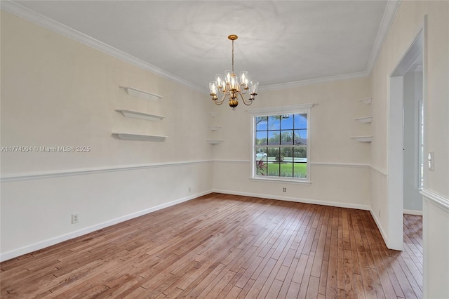 spare room with crown molding, baseboards, a notable chandelier, and hardwood / wood-style flooring