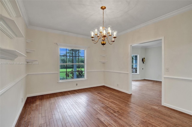 spare room featuring wood-type flooring, ornamental molding, baseboards, and a chandelier