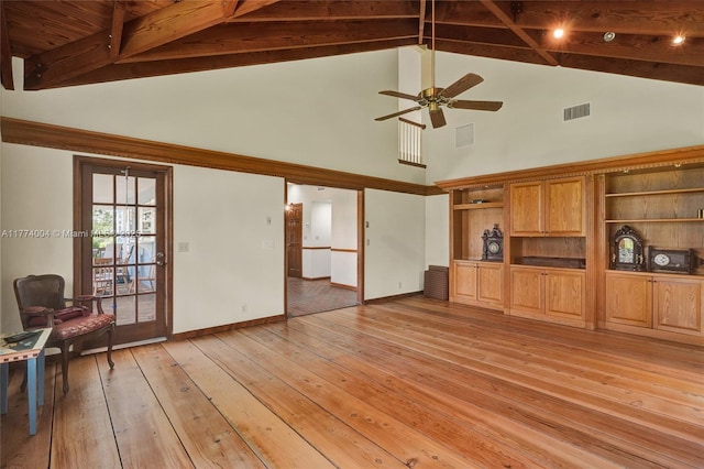 unfurnished living room featuring ceiling fan, visible vents, high vaulted ceiling, beamed ceiling, and light wood-style flooring