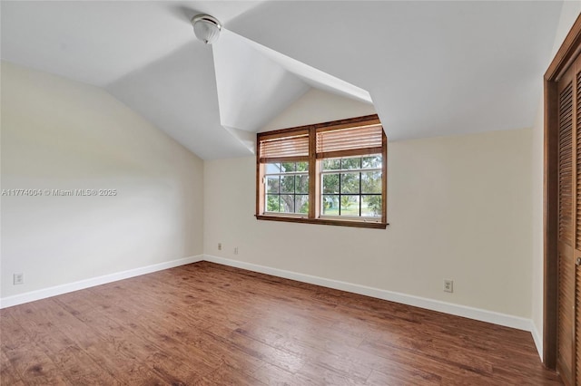 additional living space with baseboards, wood finished floors, and lofted ceiling