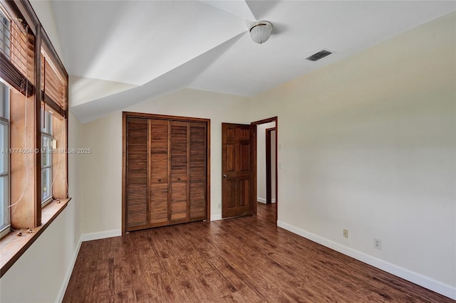 unfurnished bedroom with baseboards, visible vents, wood finished floors, and a closet