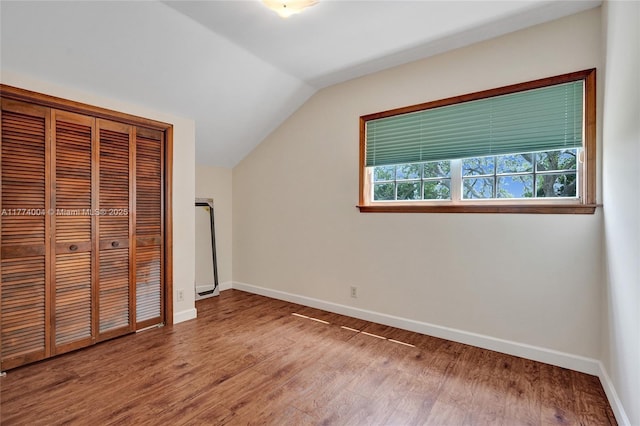 unfurnished bedroom featuring baseboards, wood finished floors, and lofted ceiling