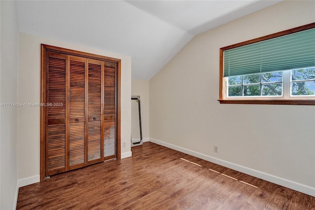 unfurnished bedroom with baseboards, vaulted ceiling, wood finished floors, and a closet