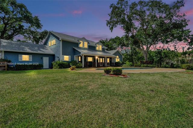 rear view of house featuring a lawn, an outdoor pool, and stucco siding