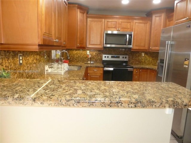 kitchen with light stone counters, a sink, and appliances with stainless steel finishes