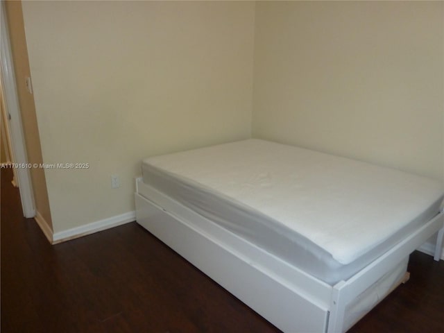 bedroom with baseboards and dark wood-type flooring
