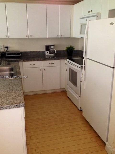kitchen featuring white appliances, light wood-type flooring, white cabinets, and a sink