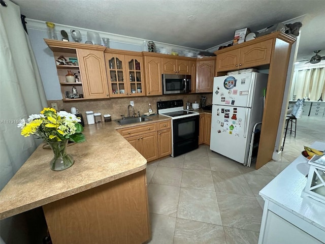 11537 SW 6th St, Sweetwater, FL 33174 - kitchen featuring stainless steel microwave, a sink, backsplash, range with electric stovetop, and freestanding refrigerator