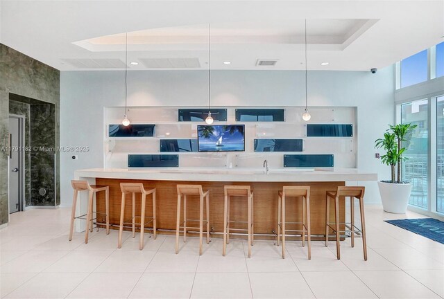 1900 N Bayshore Dr Unit 2816, Miami, FL 33132 - kitchen featuring light tile patterned floors, decorative light fixtures, a tray ceiling, a breakfast bar area, and recessed lighting