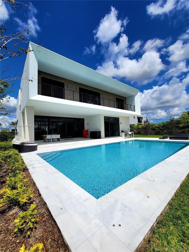 16512 Botaniko Dr S, Weston, FL 33326 - rear view of property featuring a patio, stucco siding, a balcony, and an outdoor pool
