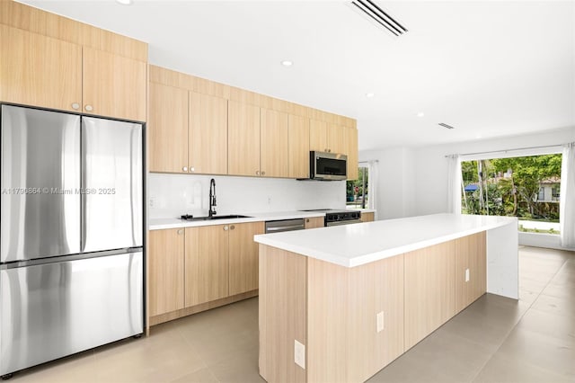 701 NE 119th St, Biscayne Park, FL 33161 - kitchen with stainless steel appliances, a sink, light brown cabinets, light countertops, and a center island