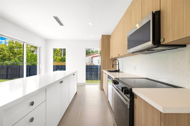 701 NE 119th St, Biscayne Park, FL 33161 - kitchen with black range with electric stovetop, stainless steel microwave, a sink, healthy amount of natural light, and recessed lighting