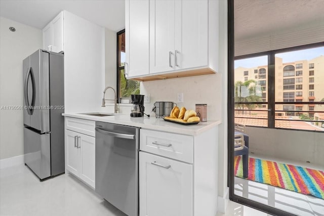 7153 Promenade Dr Unit 302, Boca Raton, FL 33433 - kitchen with stainless steel appliances, a sink, white cabinets, light countertops, and baseboards