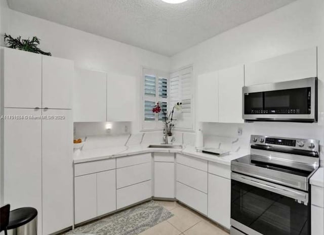 15533 N Miami Lakeway N Unit 101-19, Miami Lakes, FL 33014 - kitchen with a textured ceiling, light countertops, a sink, stainless steel appliances, and white cabinetry