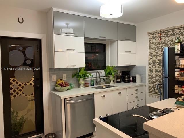 2 NE 44th St, Miami, FL 33137 - kitchen featuring a sink, stainless steel dishwasher, decorative backsplash, and freestanding refrigerator