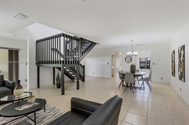 living room featuring an inviting chandelier, light tile patterned flooring, stairs, visible vents, and baseboards