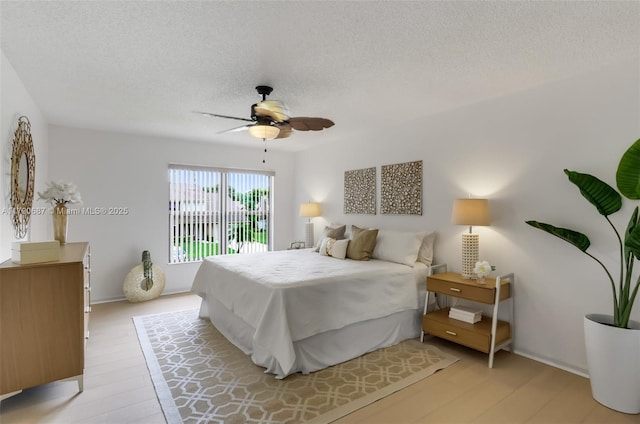 bedroom with a textured ceiling, light wood-style floors, and ceiling fan
