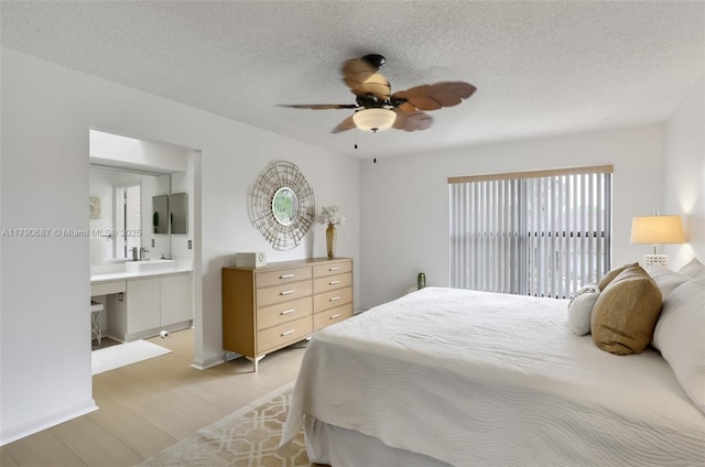 bedroom featuring a sink, light wood finished floors, a textured ceiling, and ceiling fan