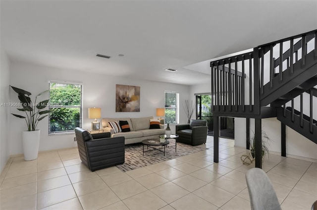 living area with visible vents, light tile patterned floors, and stairs