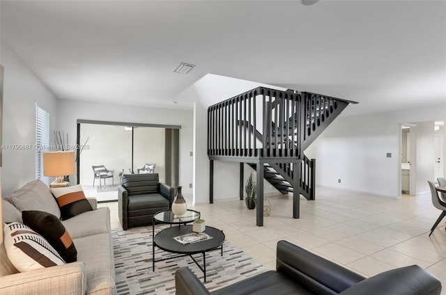 living room with visible vents, light tile patterned floors, and stairway