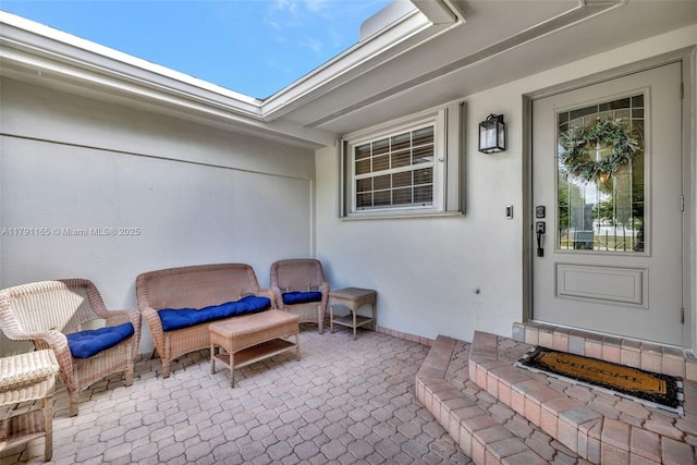 view of exterior entry with stucco siding and a patio area