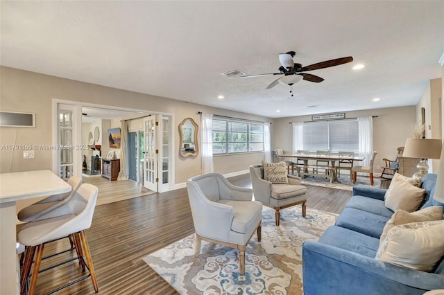 living area with baseboards, visible vents, wood finished floors, and ceiling fan