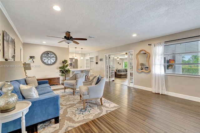living area featuring baseboards, wood finished floors, a ceiling fan, and a textured ceiling