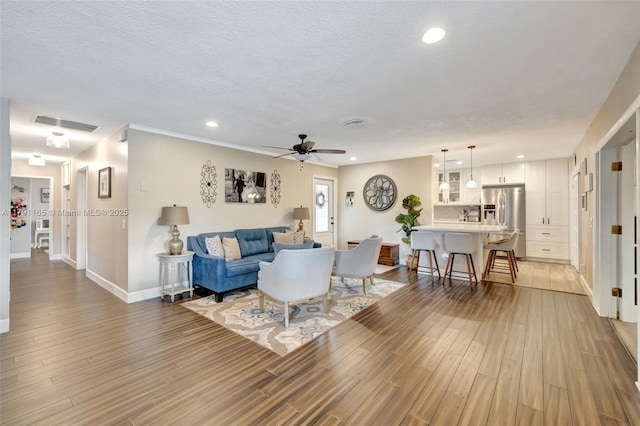 living room with baseboards, wood finished floors, a ceiling fan, and a textured ceiling