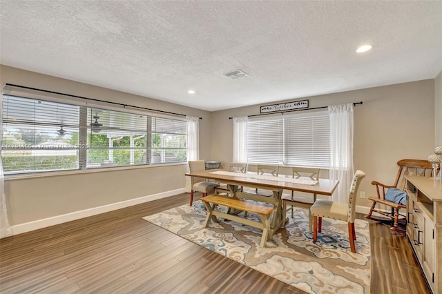 dining room featuring baseboards, visible vents, wood finished floors, and a textured ceiling