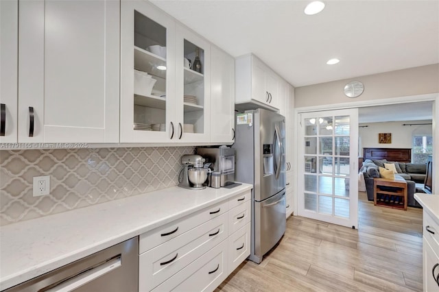 kitchen with dishwashing machine, decorative backsplash, stainless steel fridge, and white cabinetry