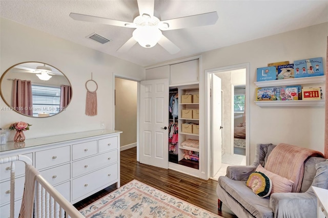 bedroom with dark wood-style flooring, visible vents, a ceiling fan, and a closet