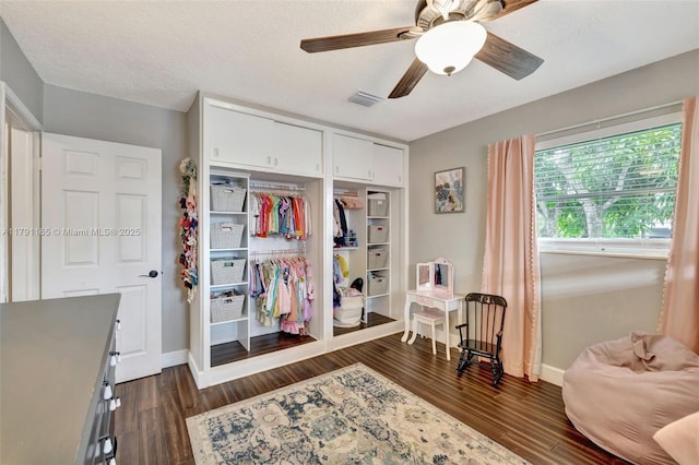 bedroom with dark wood-style floors, visible vents, ceiling fan, and a closet
