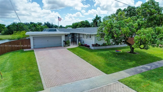 ranch-style home with fence, decorative driveway, a front lawn, and a garage