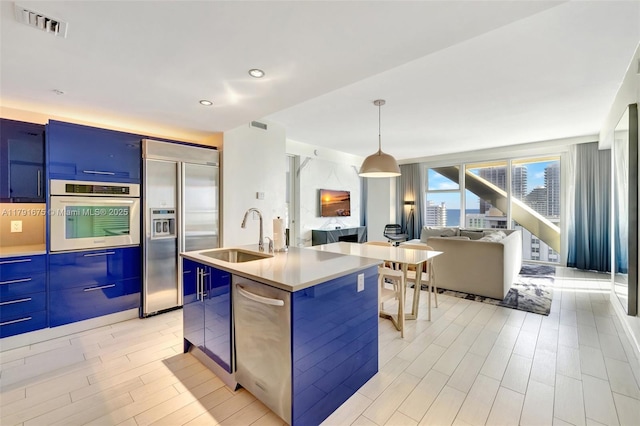 kitchen featuring blue cabinets, appliances with stainless steel finishes, a sink, open floor plan, and modern cabinets