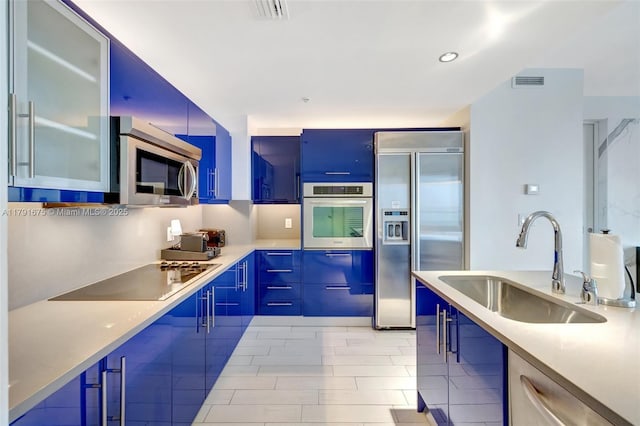 kitchen featuring appliances with stainless steel finishes, light countertops, a sink, visible vents, and modern cabinets
