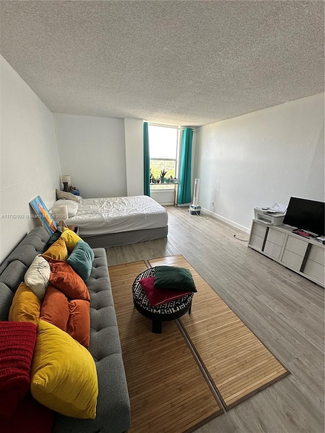 bedroom with a textured ceiling, wood finished floors, and baseboards