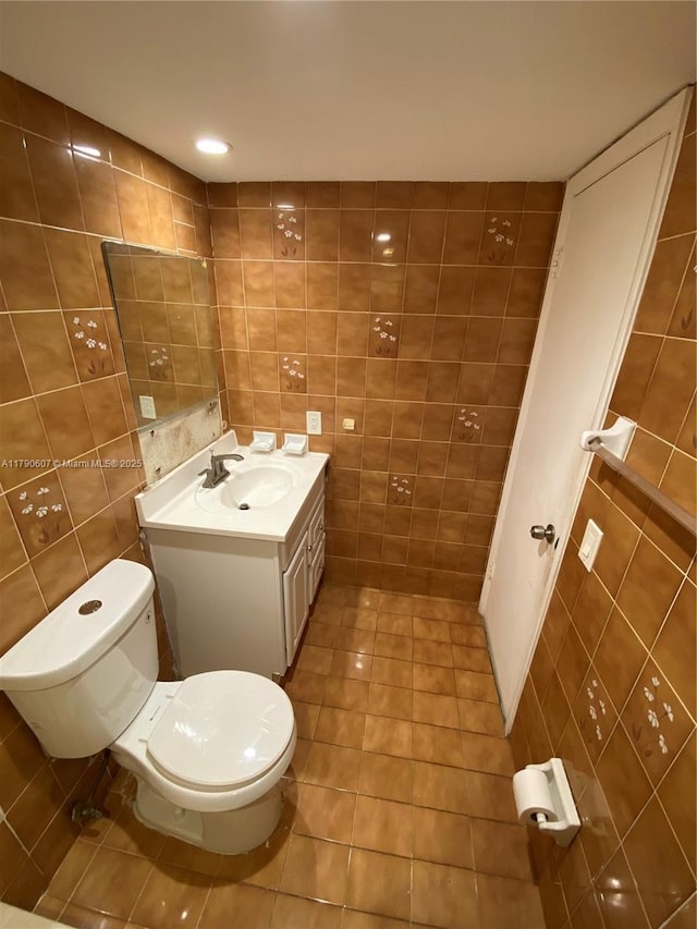 half bath featuring tile walls, toilet, tile patterned flooring, and vanity