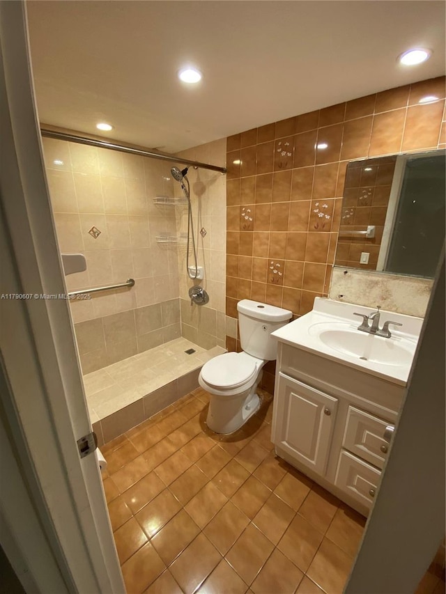 full bath featuring a tile shower, toilet, tile walls, vanity, and tile patterned flooring