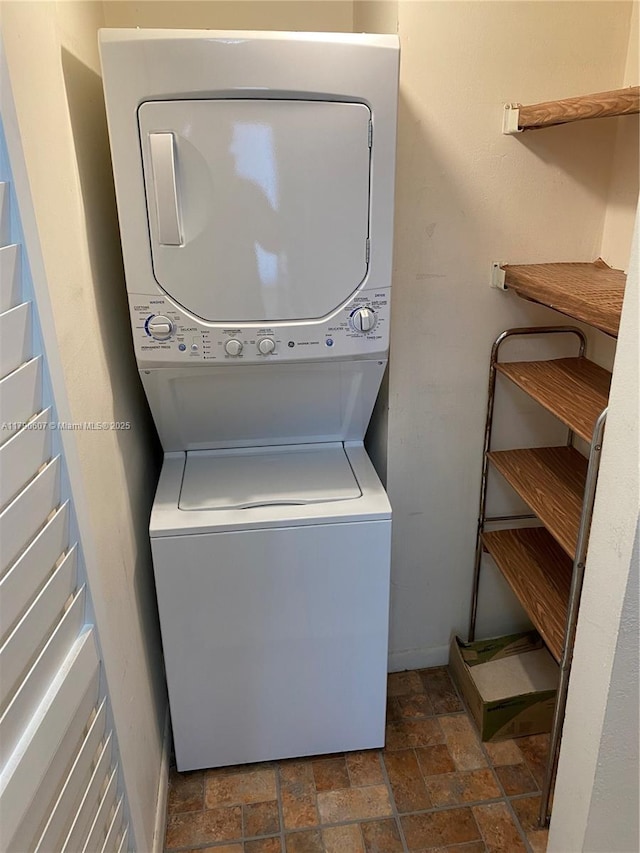 laundry area with stone finish floor, stacked washer and dryer, and laundry area