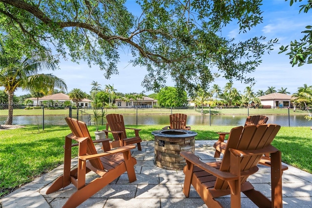 view of patio / terrace featuring fence, a fire pit, and a water view