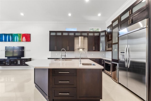 kitchen with built in appliances, light tile patterned floors, wall chimney exhaust hood, and a sink