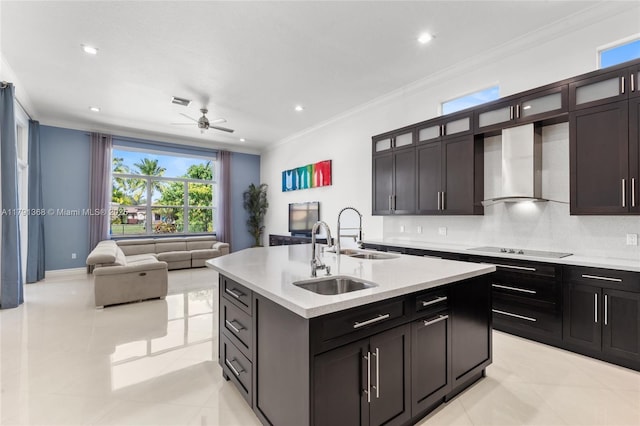 kitchen featuring a healthy amount of sunlight, a sink, a ceiling fan, wall chimney exhaust hood, and crown molding