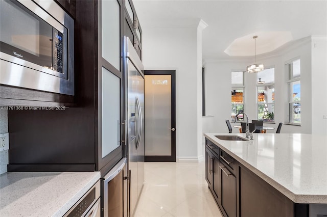 kitchen with crown molding, a sink, appliances with stainless steel finishes, light tile patterned flooring, and light stone countertops