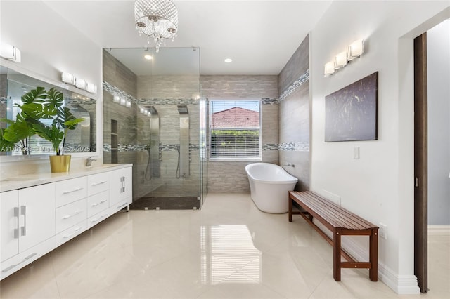 full bath with an inviting chandelier, a freestanding bath, a shower stall, tile walls, and vanity