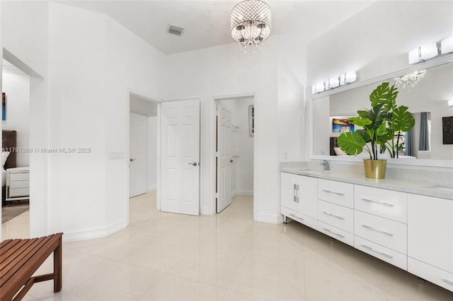 full bath featuring a sink, double vanity, visible vents, baseboards, and a notable chandelier