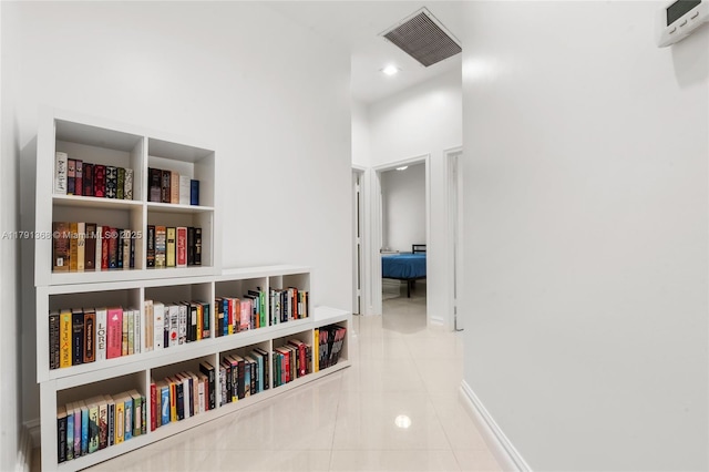 hall featuring baseboards, visible vents, and tile patterned flooring