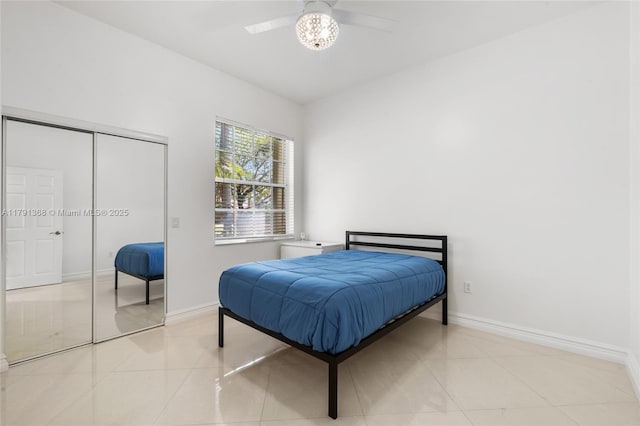 bedroom with light tile patterned floors, a closet, a ceiling fan, and baseboards