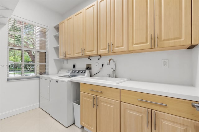 clothes washing area with light tile patterned flooring, independent washer and dryer, a sink, and cabinet space