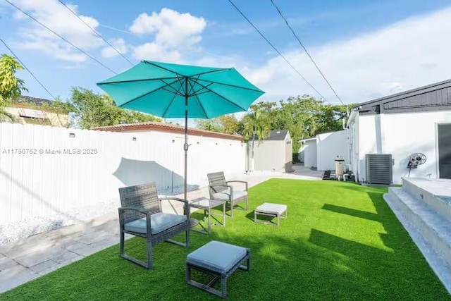 view of yard featuring a shed, a fenced backyard, central AC unit, and an outbuilding