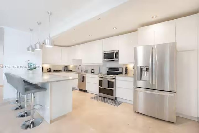 kitchen featuring modern cabinets, a kitchen bar, white cabinetry, light countertops, and appliances with stainless steel finishes